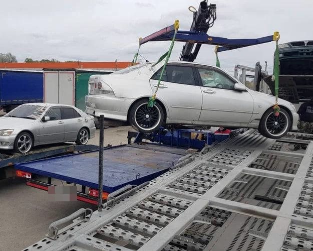 Манипулятор переставляет легковой автомобиль на автовоз